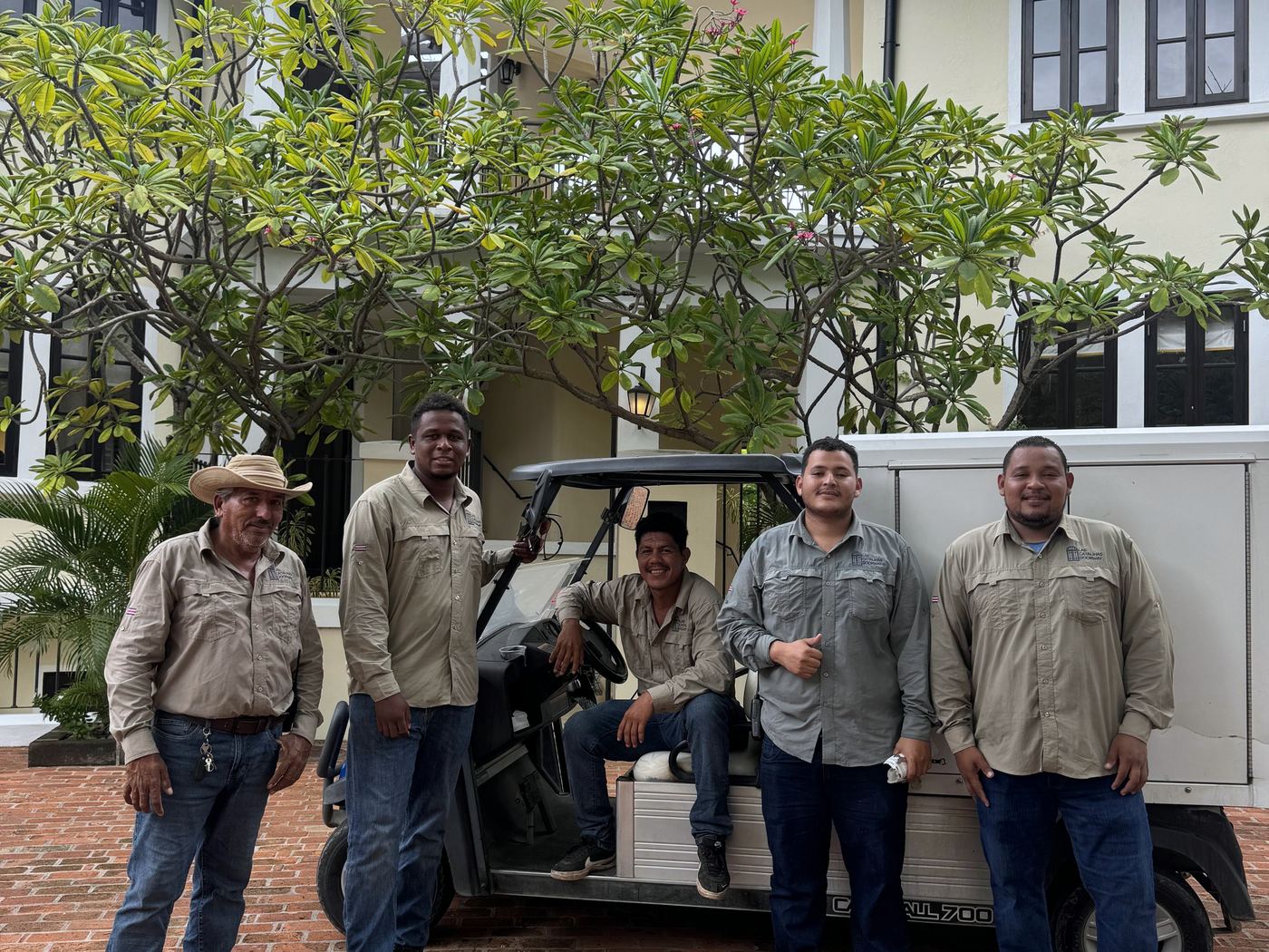 A grounds crew in matching estate shirts beside a utility cart at a villa